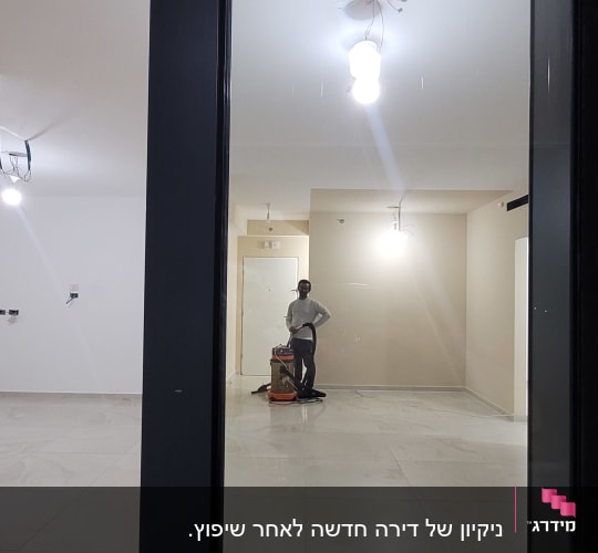 אדם עם מכונת ניקוי בחדר ריק ומואר